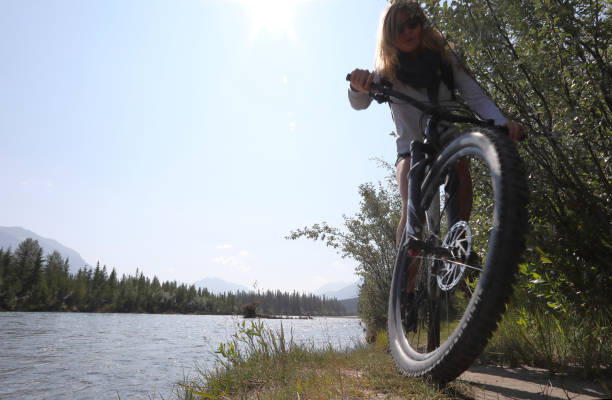 istock Young woman bikes along mountain creek 1060969380