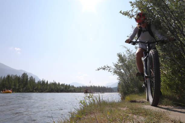 istock Young woman bikes along mountain creek 1060969382