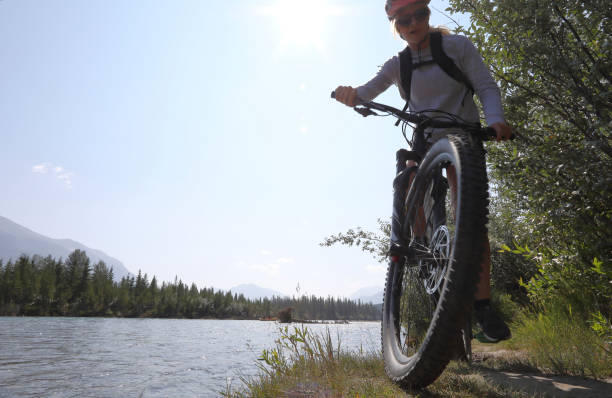 istock Young woman bikes along mountain creek 1060969402