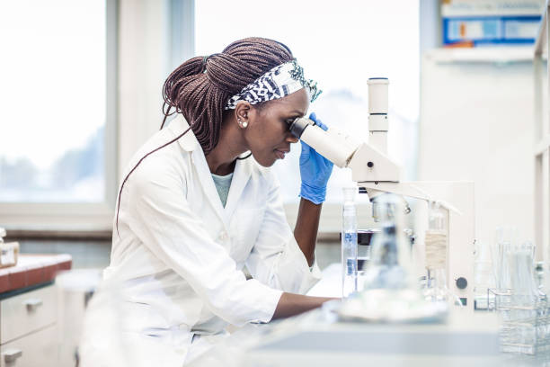 mujer científico trabajando en el laboratorio, utilizando un microscopio - scientist chemist doctor lab coat fotografías e imágenes de stock