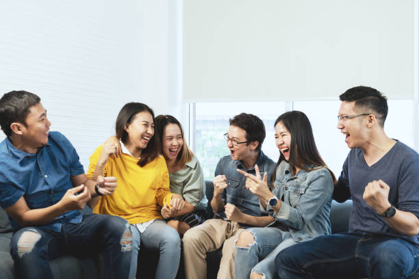 친구 이야기와 행복과 웃음의 영 매력적인 아시아 그룹 모임 회의 집에 앉아 있는 기분이 명랑 하 고 함께 여가 시간에 게임을 즐길 수 있습니다. 파란색 또는 노란색을 입고 있는 사람들. - humor men laughing teenager 뉴스 사진 이미지