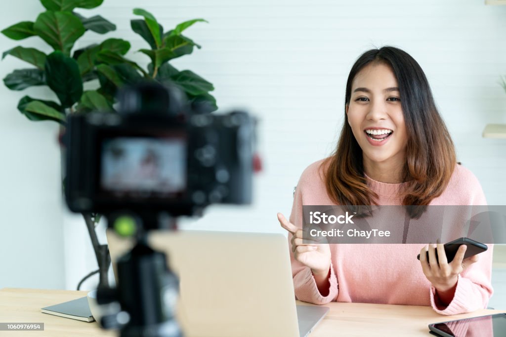 Jeune femme asiatique attrayant blogger ou vlogger regardant la caméra et parler au tournage vidéo avec la technologie. Les médias sociaux influenceur personnes ou contenu maker concept dans relax style décontracté à la maison. - Photo de Influenceur libre de droits