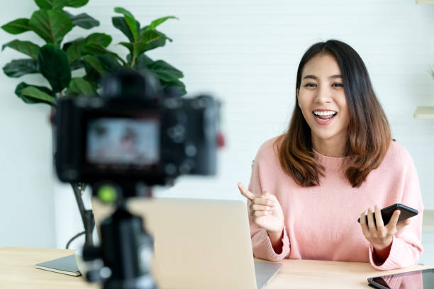 Young attractive asian woman blogger or vlogger looking at camera and talking on video shooting with technology. Social media influencer people or content maker concept in relax casual style at home. Young attractive asian woman blogger or vlogger looking at camera and talking on video shooting with technology. Social media influencer people or content maker concept in relax casual style at home. influencer stock pictures, royalty-free photos & images