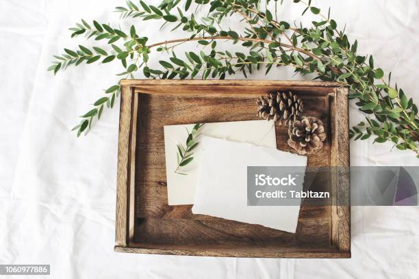 Christmas Or Winter Wedding Mockup Scene Blank Cotton Paper Greeting Cards Old Wooden Tray Pine Cones And Green Eucalyptus Parvifolia Branchwhite Bed Linen Background Flat Lay Top View Stock Photo - Download Image Now