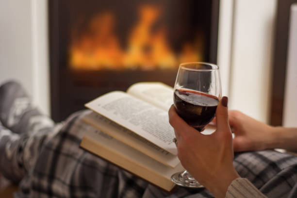 femme lisant livre et boire du vin rouge devant la cheminée - blanket fireplace winter women photos et images de collection