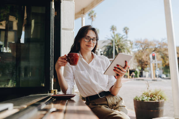 бизнесвумен в кафе с чашкой кофе и цифровым планшетом - e reader digital tablet cafe reading стоковые фото и изображения