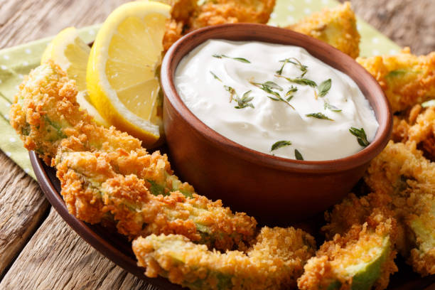 Deep-fried avocado in breadcrumbs closeup and cream sauce. horizontal