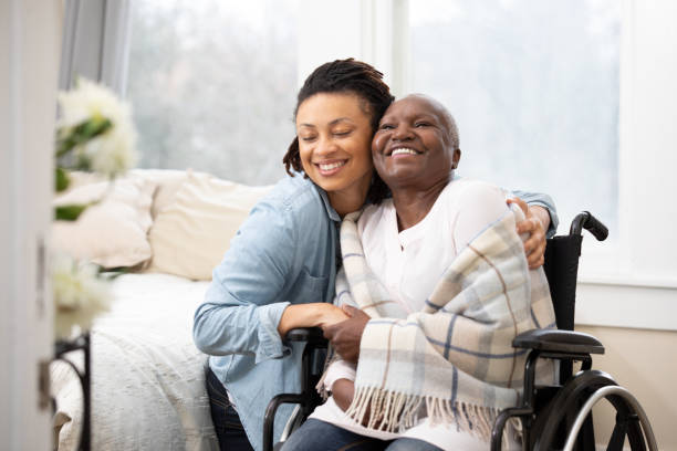 jeune femme hugs senior femme en fauteuil roulant - women mother african descent daughter photos et images de collection