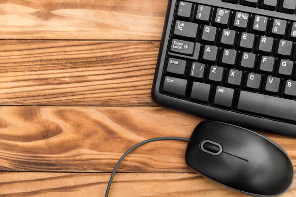 istock Computer mouse and keyboard on wooden background. Top view. Space for text. 1060998486
