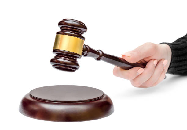 Female's hand holding judge's gavel over stand. Law concept. stock photo