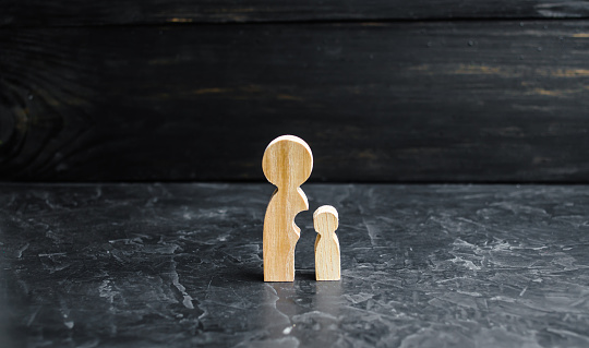 Wooden figures of mother and child. The baby is separated from the mothers body. The concept of maturation and self-reliance. Under the wing of the mother. Child education.