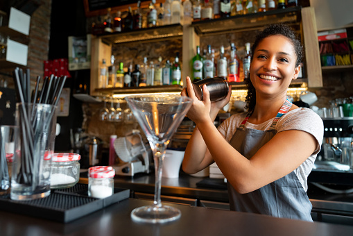 Portrait of a happy female bartender mixing drinks at a bar in a cocktail mixer