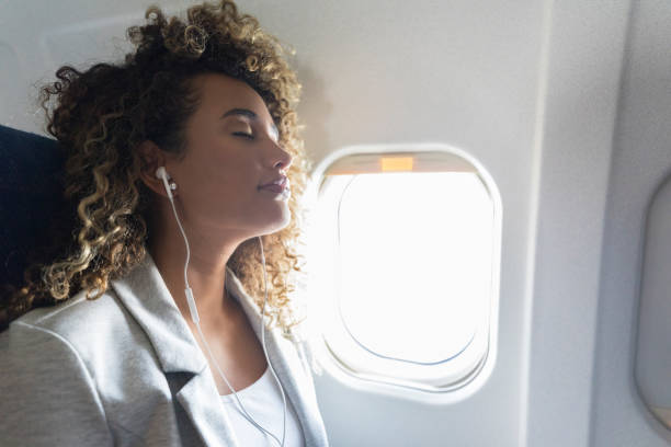 istock Young woman sleeps with earbuds on airplane 1061010596