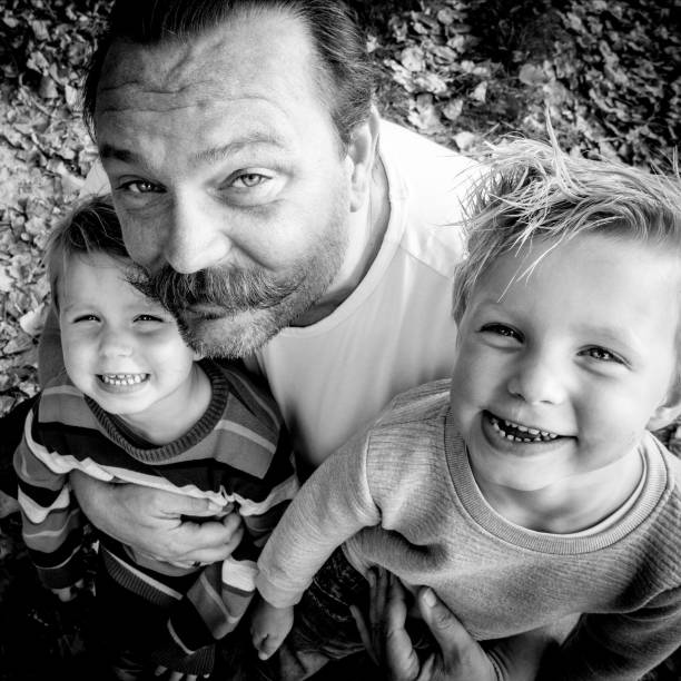 father and his toddler sons - black and white portrait stock photo