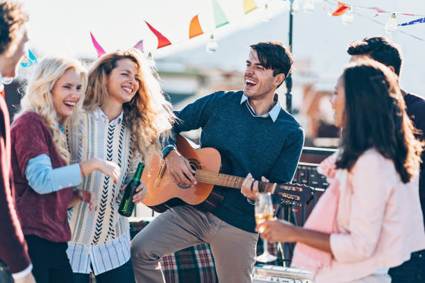istock Man playing guitar for his friends on a rooftop party 1061013860