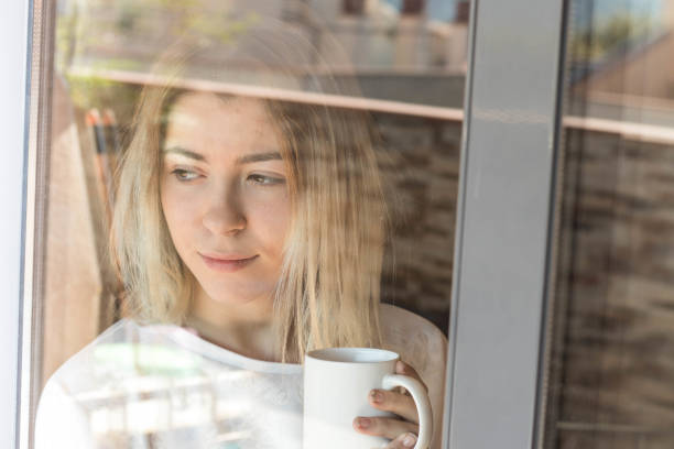 istock Girl looking through a window with coffee 1061017132