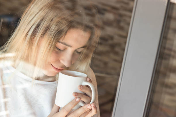 istock Girl looking through a window with coffee 1061017152