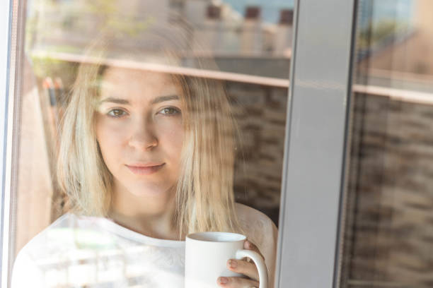 istock Girl looking through a window with coffee 1061017156