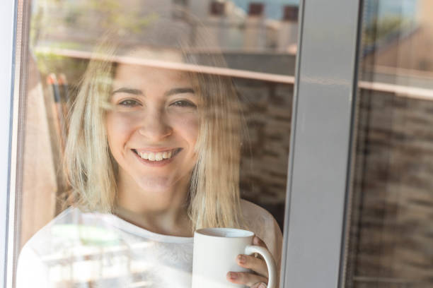 istock Girl looking through a window with coffee 1061017166