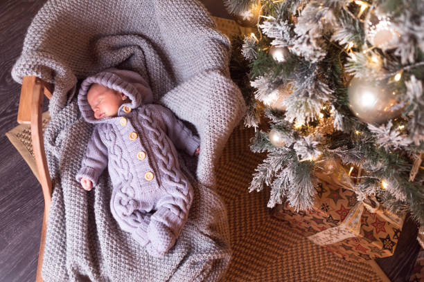 Baby boy sleeping under the Christmas tree on New Year's Eve