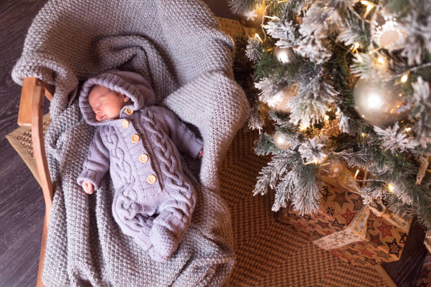 Baby boy sleeping under the Christmas tree on New Year's Eve stock photo