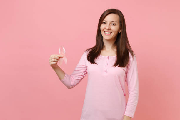 Woman in rose clothes hold in hand pink silk ribbon isolated on pastel wall background, studio portrait. Medical healthcare gynecological oncology, Breast Cancer Awareness concept. Mock up copy space mujer en ropa rosa mantenga la cinta de seda color de rosa en la mano aislada sobre fondo de pared pastel, retrato de estudio. médica oncología ginecológica salud, concepto de concientización del cáncer de mama. se burlan de espacio de copia.
