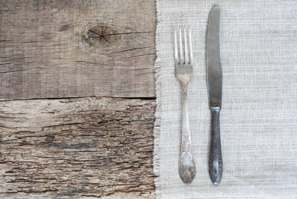 istock Fork and gray canvas knife on a napkin and old boards. Rustic, copy space 1061027020