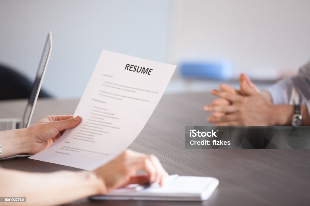 Hr holding reading resume at job interview, close up view Hands of hr holding paper resume at job interview, recruiter or employer reading cv application of vacancy candidate during hiring negotiations, employment and staff recruiting concept, close up view Résumé Stock Photo