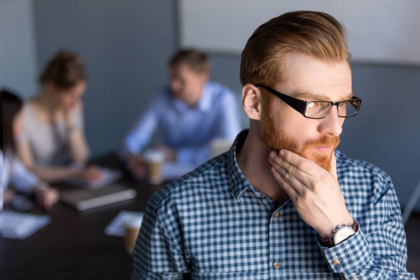 Thoughtful businessman looking away holding hand on chin planning project