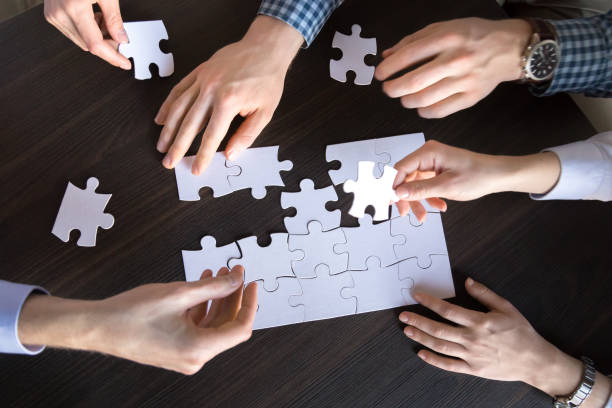 istock Top close up view of hands engaged in assembling puzzle 1061027998