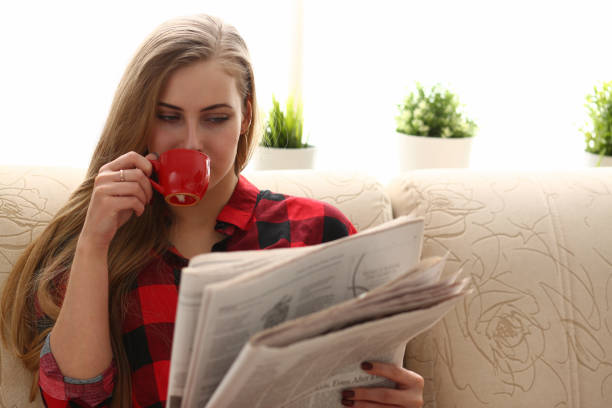 istock woman drinking coffe and reading sit on sofa 1061030414