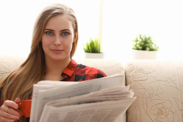 istock woman drinking coffe and reading sit on sofa 1061030424