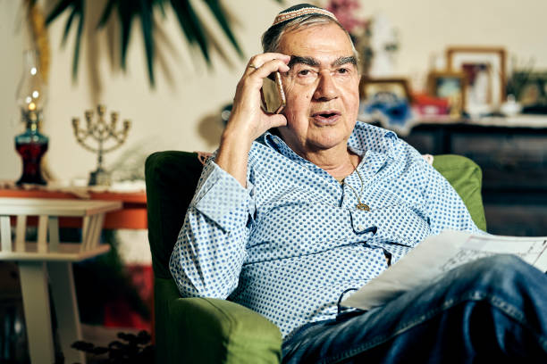 istock Jewish senior talking on the phone and reading a torah book 1061040412