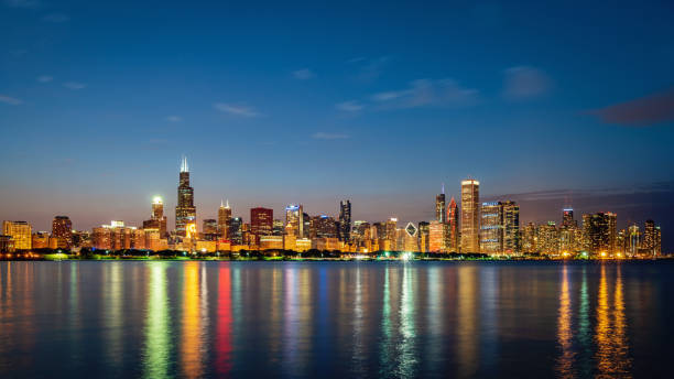 Chicago Skyline Panorama Lake Michigan Reflections at Night Panorama of Illuminated Cityscape, Skyline of Chicago at Twilight, Night. Modern urban skyscraper lights mirroring in the Lake Michigan water. Long Exposure. Chicago, Illinois, USA. lake shore drive chicago stock pictures, royalty-free photos & images