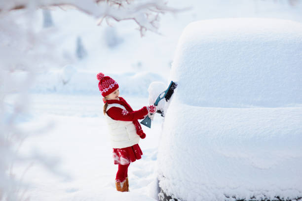 istock Child brushing off car. Kid with winter snow brush 1061049958