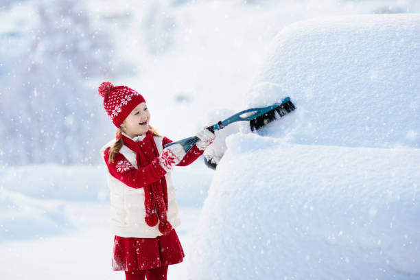 istock Child brushing off car. Kid with winter snow brush 1061051836