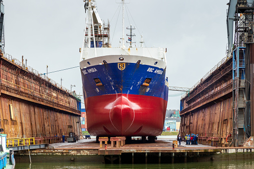 ROTTERDAM, NETHERLANDS - SEP 5, 2015: Dock workers at work on a vessel hull in a ship repair drydock.