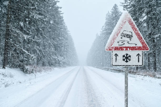istock Winter Driving - Snowy Road with Warning Sign 1061062610
