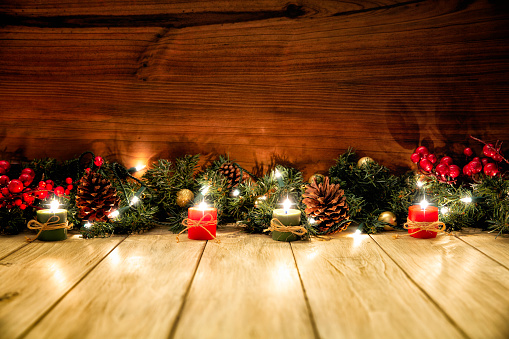 Colorful Christmas candle and adorns on rustic wooden background with copy space. Christmas is a time for family and friends to get together and exchange gifts.  A Christian holiday honoring the birth of Jesus Christ, Christmas evolved over two millennia into a worldwide religious and secular celebration. Christmas Day is a holiday in many, but not all, countries. Many homes have Christmas trees and other decorations in the weeks leading to Christmas Day. Some workplaces hold Christmas parties prior to December 25.