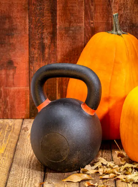 kettlebell and pumpkins against weather, red painted barn wood