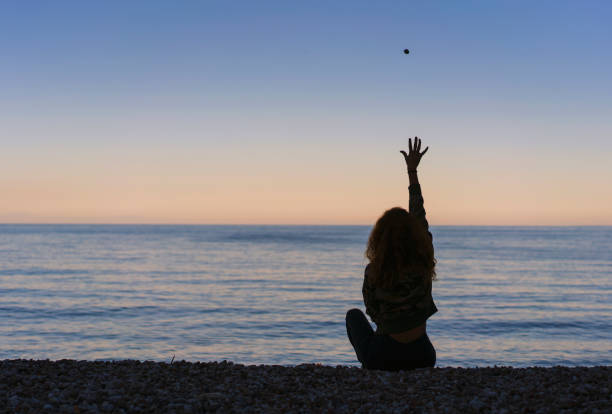 Hipster young woman throwing a stone into the sea, Antalya, Turkey