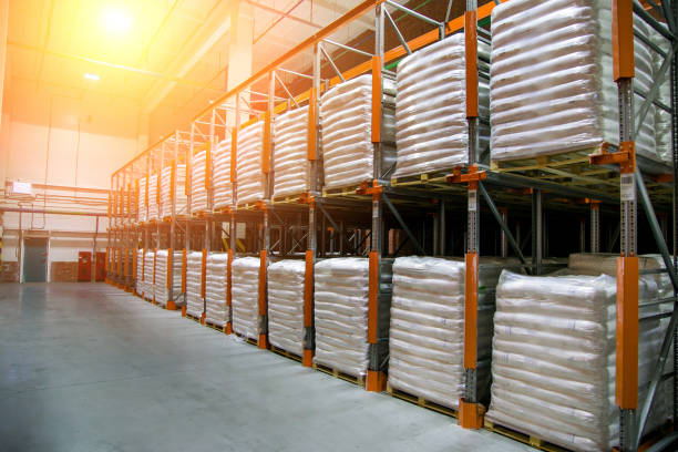 Hangar warehouse with rows of shelves with white polyethylene bags with finished factory production Hangar warehouse with rows of shelves with white polyethylene bags with finished factory production. cement bag stock pictures, royalty-free photos & images