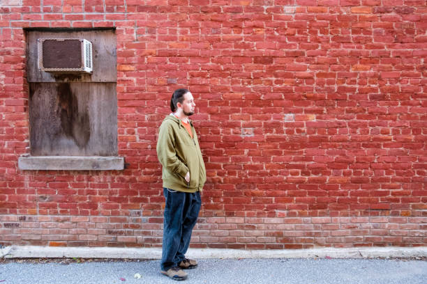 Man Standing In Front Of An Old Brick Wall With Copy Space Man Standing In Front Of An Old Brick Wall With Copy Space boarded up photos stock pictures, royalty-free photos & images