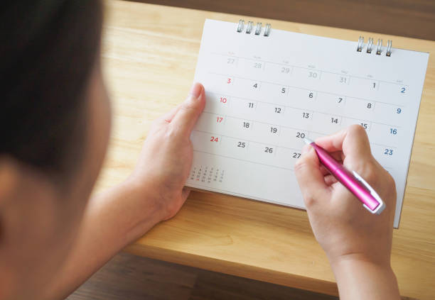istock calendar page with female hand holding pen on desk table 1061085190