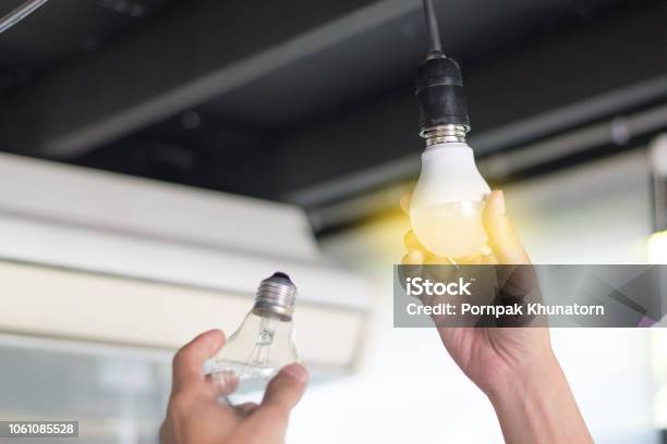 Power Saving Concept Asia Man Changing Compactfluorescent Bulbs With New Led Light Bulb Stock Photo - Download Image Now