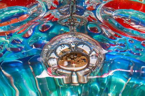 Pocket watch submersed in water and distorted by water drops - macro photography