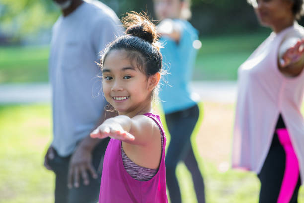 istock Elementary age Asian girl doing yoga poses during outdoor exercise class 1061126030