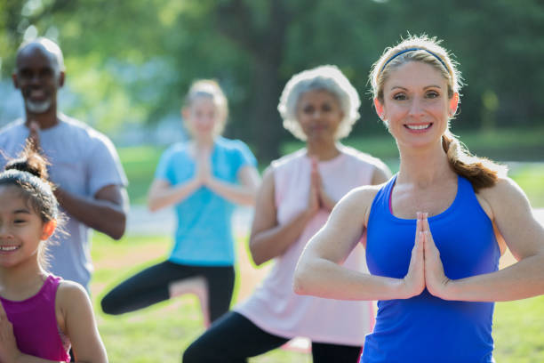 mid femme adulte enseigner des cours d’yoga en plein air aux étudiants divers - senior adult comfortable relaxation latin american and hispanic ethnicity photos et images de collection