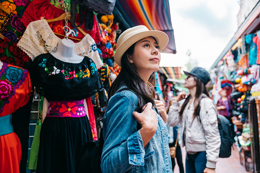traveler shopping in the traditional market and thinking what to buy for souvenirs in Mexican street. beautiful tourist being attracted by the beauty of the blue sky. tourists standing in outdoor.