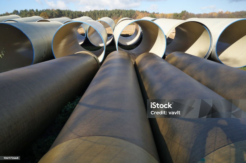 Large sewer pipes  lie on sand and dirt  in a autumn forest  construction site.  Sunny October day Large sewer pipes  lie on sand and dirt  in a autumn forest  construction site.  Sunny October day outoor industrial shots Pipe - Tube Stock Photo